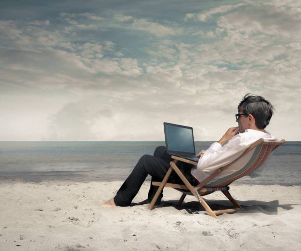 istock Person working on his laptop on the beach 1439777086