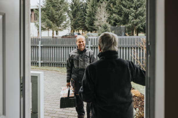 Electrician talking to a customer on the porch of the house Photo series of a electrician's workday. Meeting the client to install 5g internet connection. door repairman men manual worker stock pictures, royalty-free photos & images