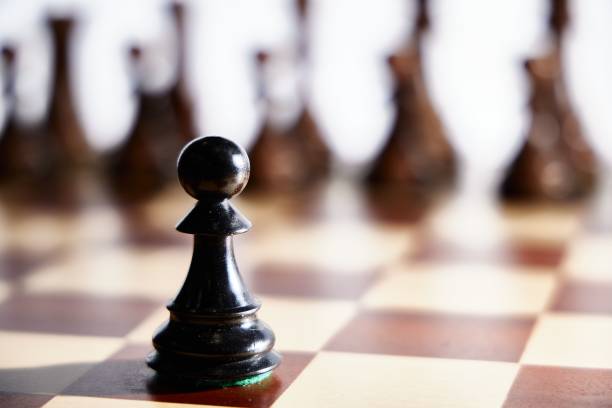 istock Black chess pawn on a wooden board - intimidation, strategy concept 1439778806