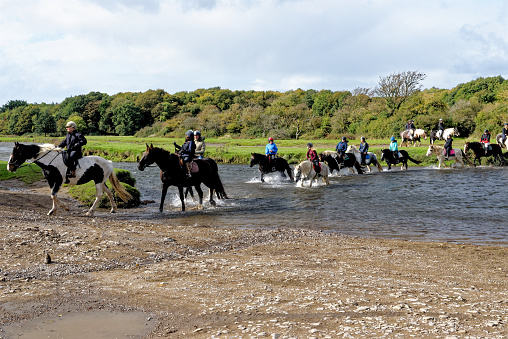 Riders crossing the river Ewenny Ogmore Castle. Ogmore by Sea, Glamorgan, Wales, United Kingdom - 15th of October 2022