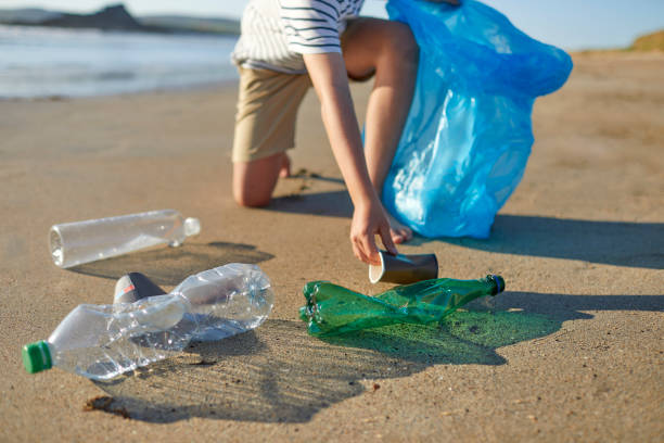 istock Boy picking up disposable coffee cup from beach 1439780056