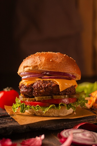 A closeup shot of a delicious all-American burger on a wooden cutting board