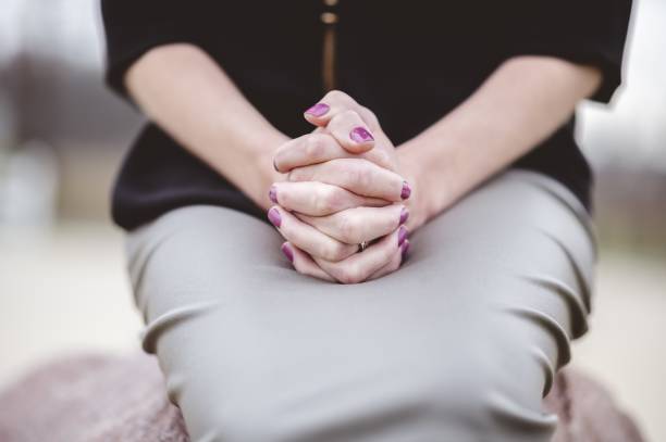 istock Woman sitting with hands together on lap while praying 1439781388