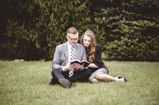 istock Romantic couple sitting on grassy lawn and lovingly reading a book 1439781413
