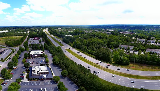 A drone view of a highway with cars and non-residential buildings on the sides