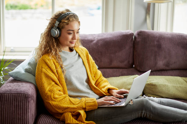 istock Beautiful blond woman using laptop on sofa at home 1439782816