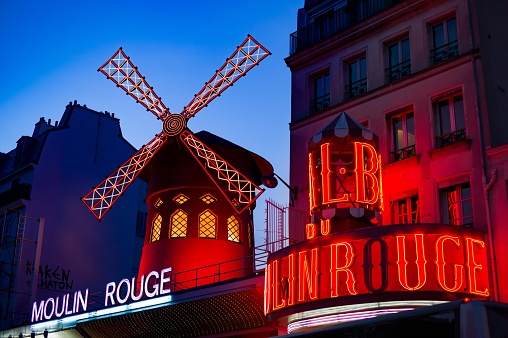 Paris, France – June 15, 2019: View of the Moulin Rouge club at night, in the historical neighborhood of Montmartre, the former red light district of Paris.