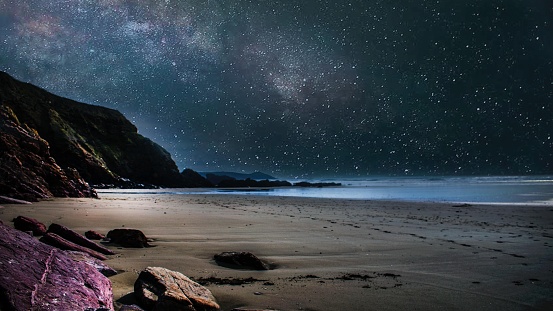 A beautiful nocturnal shot of the seashore and the sky with full of stars in Cornwall, UK