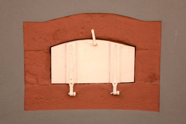 istock Closeup of a small window with a white shutter in a smoothly painted gray wall 1439785890