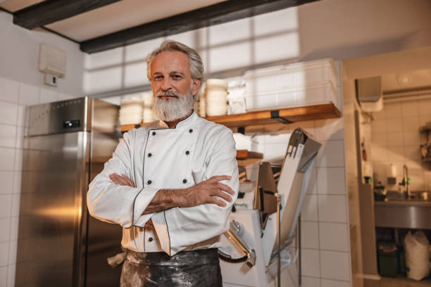 Caucasian Baker With Arms Crossed Standing In The Kitchen Of The Bakery stock photo