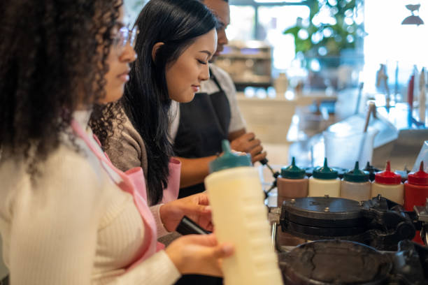 istock Diverse Group Friends Enjoy Coffee Shop Cafe Interview Work Employee Worker Waffle Making Lattes Cappuccinos 1439786656