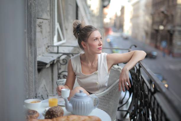 istock Attractive female wearing white sitting at a breakfast table on a balcony with a beautiful view 1439786719