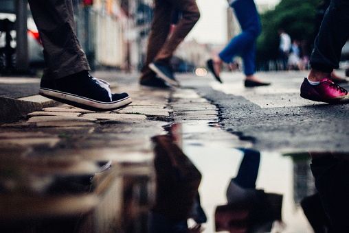 A puddle with the reflection of a group of people crossing the street