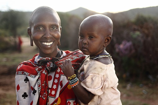 Masai Mara, Kenya – January 01, 2013: A shallow focus shot of an African mother with its baby while smiling at the camera