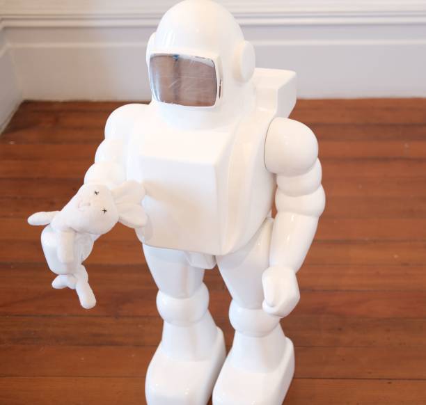 istock White robot statue holding a stuffed bunny on a wooden surface 1439787827