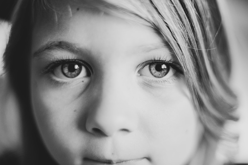 A grayscale shot of a cute little girl with beautiful eyes