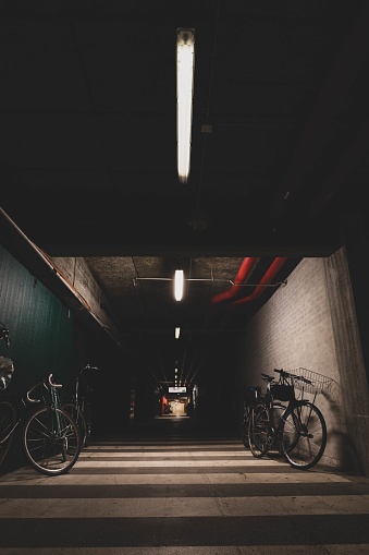 A vertical shot of bicycles parked inside the dark garage with a few lights