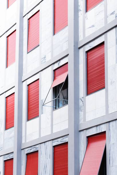 istock Vertical shot of a white building with windows with red blinds 1439789496