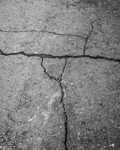 istock Cracked grey asphalt road - great for a background 1439789589