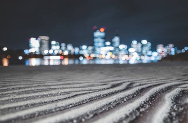 Patterns on the sand by the river with the blurred buildings in the background