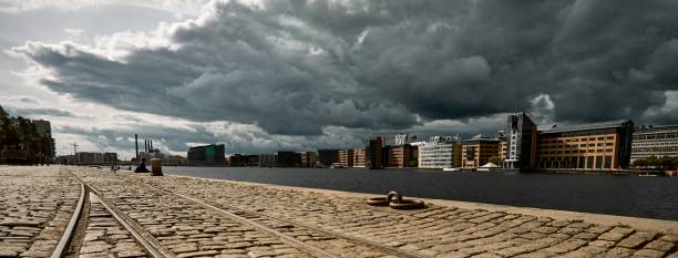 istock Low angle view of a stone road surrounded by buildings under a dark cloudy sky 1439790089