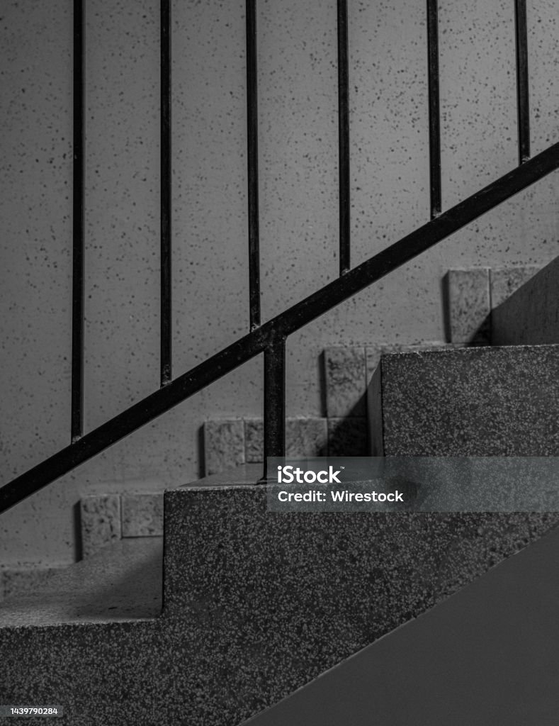 Vertical greyscale shot of concrete stairs with metal railings A vertical greyscale shot of concrete stairs with metal railings Abandoned Stock Photo