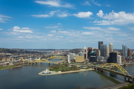 A photo of Pittsburgh from an adjacent mountain. Sunny and warm feel with scattered clouds.