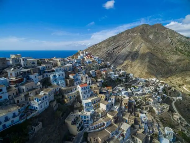 A high shot of modern white buildings in Karpathos surrounded by mountains and sea in the background