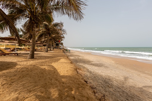 A landscape of a beach resort surrounded by palms and the sea under a blue sky in the Gambia