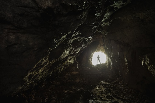 Persona parada en la salida blanca iluminada del túnel oscuro: la vida comienza a florecer concepto photo