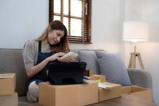 istock Startup SME small business entrepreneur woman using phone call receive from customer checking product on stock at home office, online marketing packaging delivery box, SME e-commerce concept. 1439792568