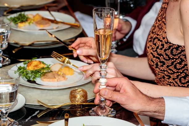 groupe de personnes assises à une table mangeant du foie gras et buvant du champagne - foie gras salt luxury restaurant photos et images de collection