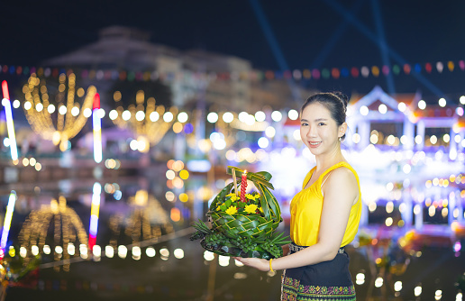Loy Krathong Traditional Festival, A beautiful Thai woman holds a Krathong ornamental form banana leafs in Loy Krathong celebrations in Thailand for the goddess of water on a full moon night.