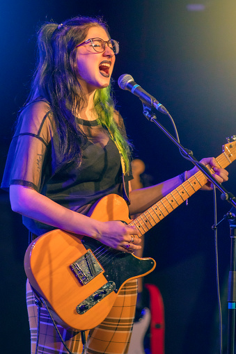 A beautiful 20 year old young woman pop punk singer/songwriter performing her music live on stage.