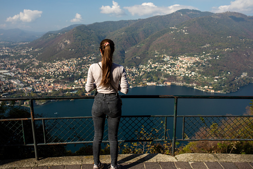Young female tourist taking photo of Como lake on a beautiful autumn sunny day