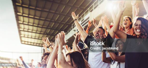 Crowd Of Sports Fans Cheering During A Match In A Stadium People Excited Cheering For Their Favorite Sports Team To Win The Game Stock Photo - Download Image Now