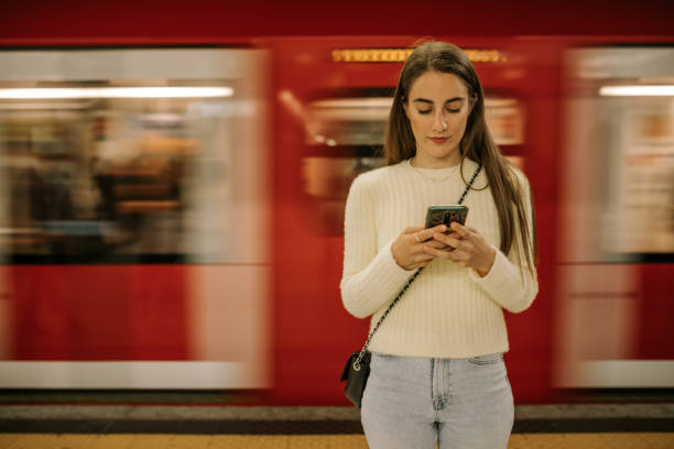 istock Young woman at metro station using mobile while waiting 1439795100