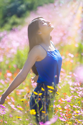Young woman feeling the sun's rays in a field of flowers