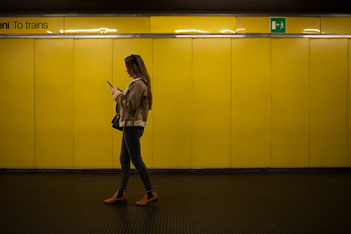 Young woman using mobile at Subway station on her way to job