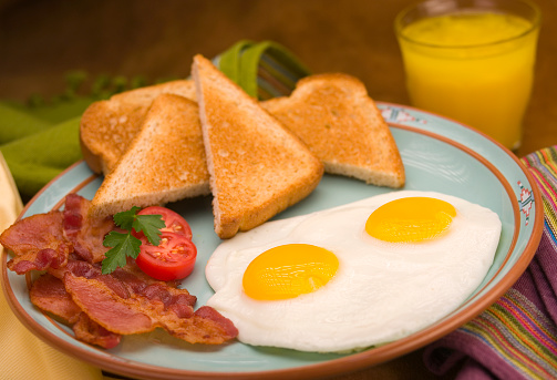 Breakfast plate with eggs, bacon, toast and OJ