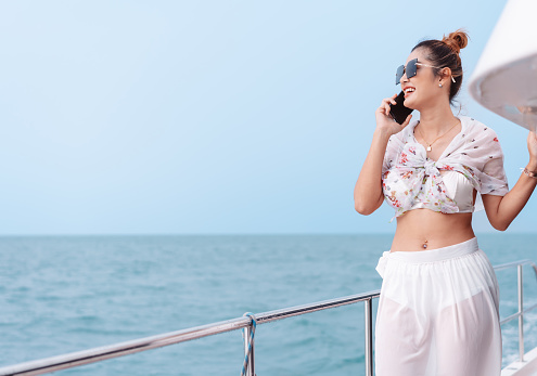 Beautiful woman calling friend with mobile phone on luxury yacht. Having fun and enjoying the sun, woman happy summer travel at sea. weekend activity lifestyle