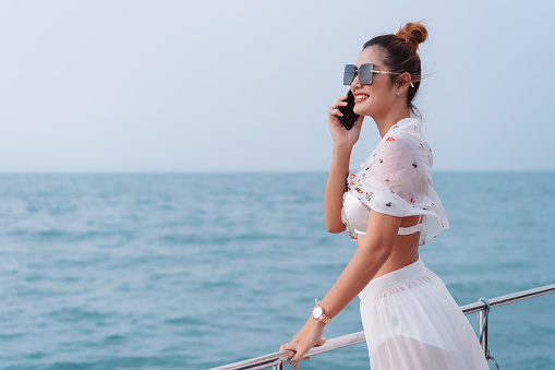Beautiful woman calling friend with mobile phone on luxury yacht. Having fun and enjoying the sun, woman happy summer travel at sea. weekend activity lifestyle