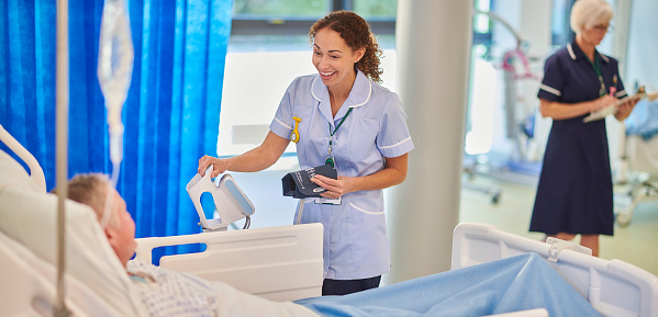 Middle aged man feeling ill admitted into clinic recieving choice of prescription painkillers on hospital bed. Doctor presenting medication bottles for treatment after surgery to recovering patient.