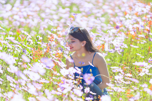 Latin woman smelling flowers in the field