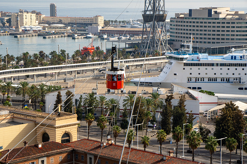 Barcelona cable car in the foreground, going down to the port and anchored cruise ships