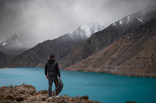 Looking at beautiful lake at rainy weather in the mountains. Iskanderkul lake, Tajikistan