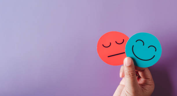 istock Hands holding sad face hiding or behind happy smiley face, bipolar and depression, mental health concept, personality, mood change, therapy healing split concept on purple background 1439800663
