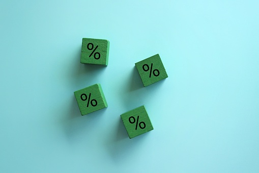 Interest rate on loan or deposit. Debt burden, high indebtedness. Savings on shopping purchases. Discounts and promotions concept. Wooden cubes and percent sign with copy space