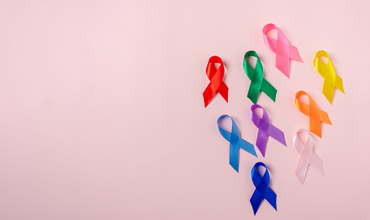 Multi colorful ribbons on pink background, cancer awareness, World cancer day, National cancer survivor day, world autism, supporting people living and illness, Prostate awareness concept.