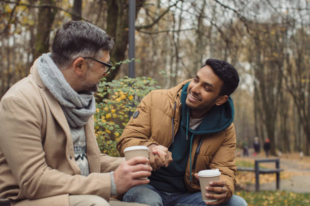 istock Smiling multiethnic men talking on bench in autumn park 1439802304